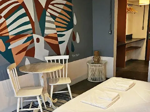 Quarto com mural de folhas, mesinha redonda e cama de casal