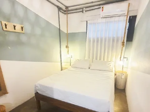 Quarto com cama de casal, luminária de palha e janela
